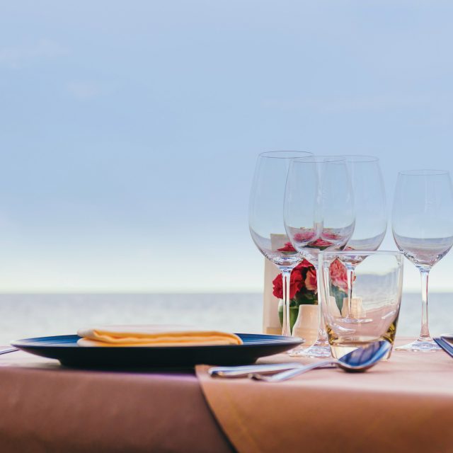 Romantic dining table setting with wine glass and other with sea and ocean background